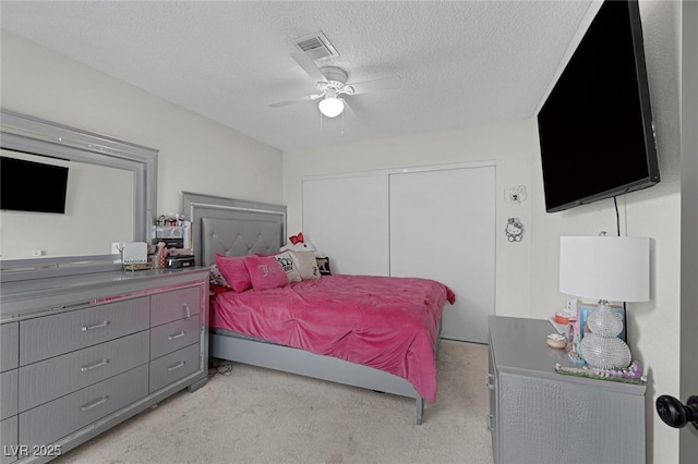 carpeted bedroom featuring ceiling fan, a closet, and a textured ceiling