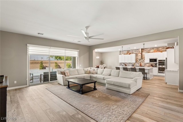 living room with ceiling fan and light wood-type flooring