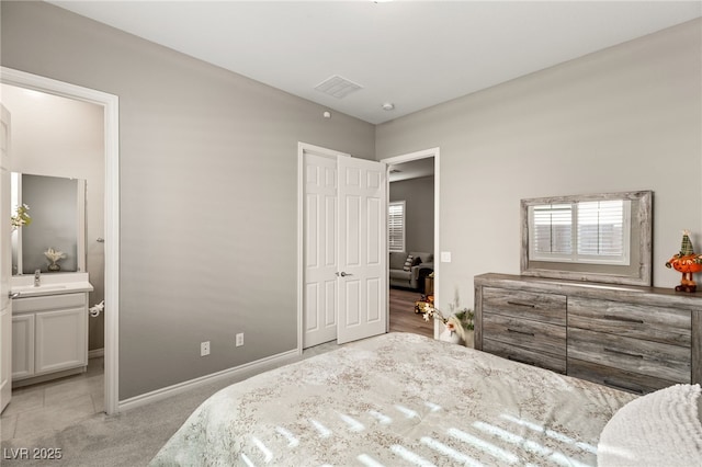 carpeted bedroom with sink, ensuite bath, and a closet