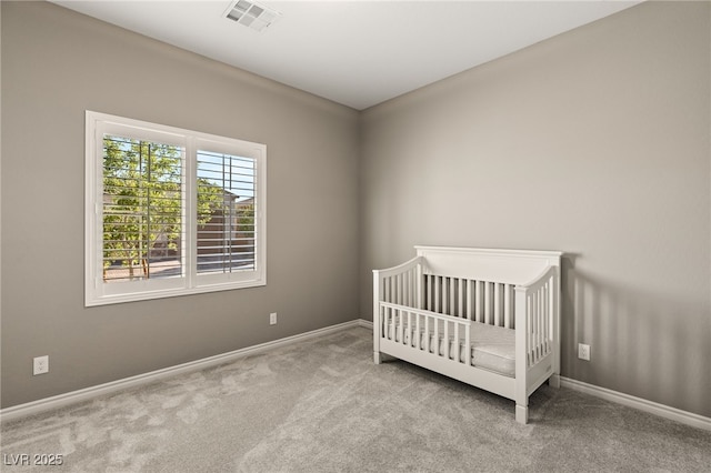 unfurnished bedroom featuring a nursery area and light colored carpet