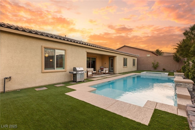 pool at dusk with a grill, a patio area, pool water feature, and a lawn