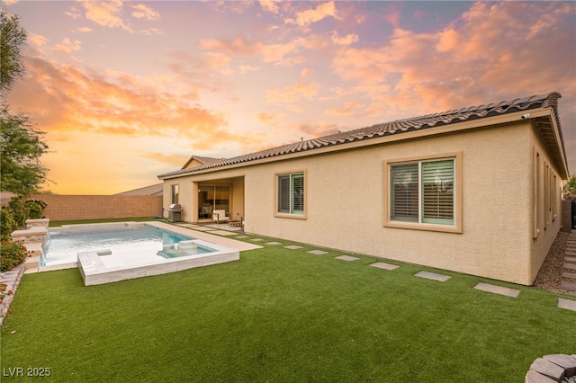 back house at dusk with a yard and a patio