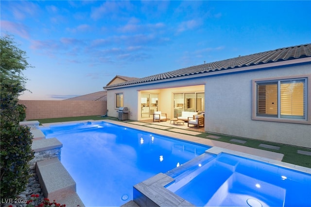 pool at dusk with an in ground hot tub, a grill, an outdoor hangout area, and a patio area