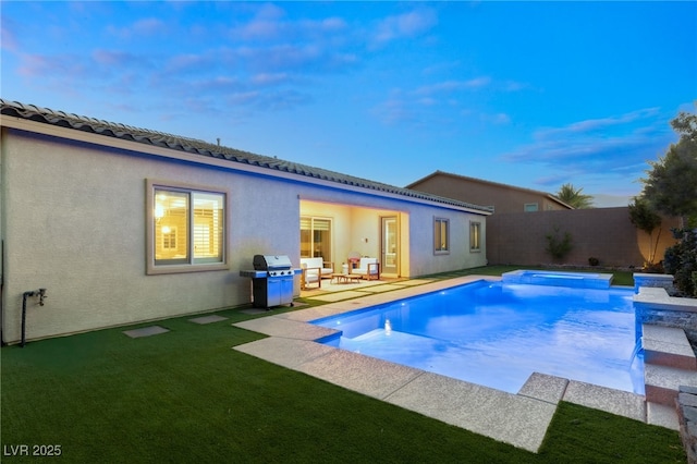 pool at dusk with a lawn, grilling area, and a patio area