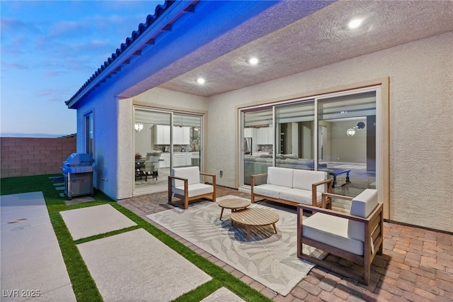 patio terrace at dusk featuring area for grilling and an outdoor living space