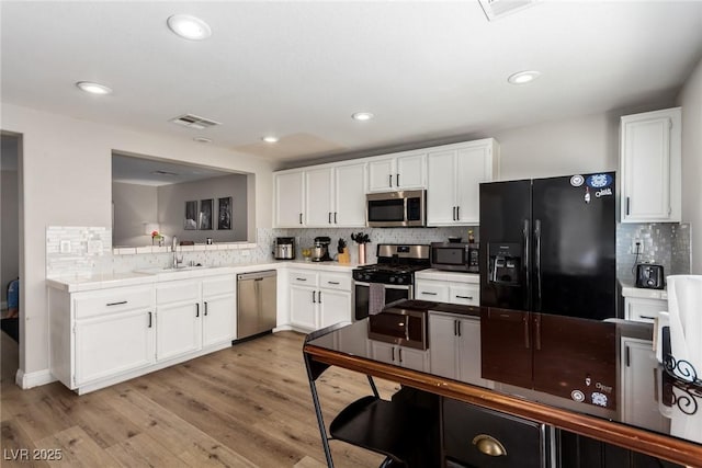 kitchen featuring white cabinetry, appliances with stainless steel finishes, sink, and light wood-type flooring