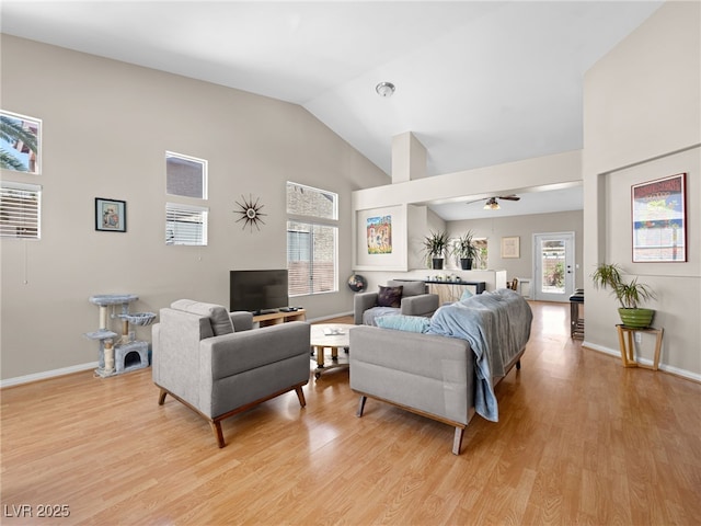 living room featuring a wealth of natural light, high vaulted ceiling, ceiling fan, and light wood-type flooring