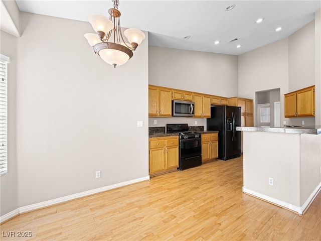 kitchen featuring an inviting chandelier, high vaulted ceiling, black appliances, decorative light fixtures, and light wood-type flooring