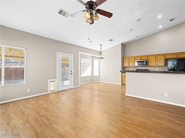 unfurnished living room featuring high vaulted ceiling, ceiling fan with notable chandelier, and light wood-type flooring