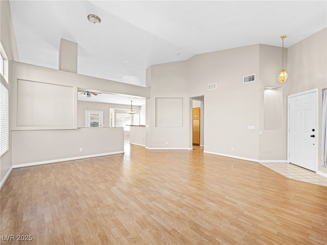 unfurnished living room featuring high vaulted ceiling and light wood-type flooring