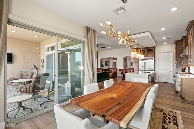 dining room with dark wood-type flooring, sink, and a notable chandelier