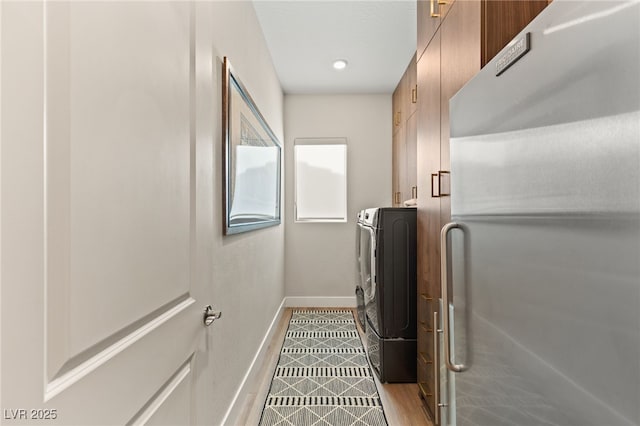 clothes washing area featuring independent washer and dryer, cabinets, and light wood-type flooring