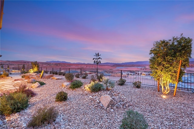 yard at dusk featuring a water and mountain view