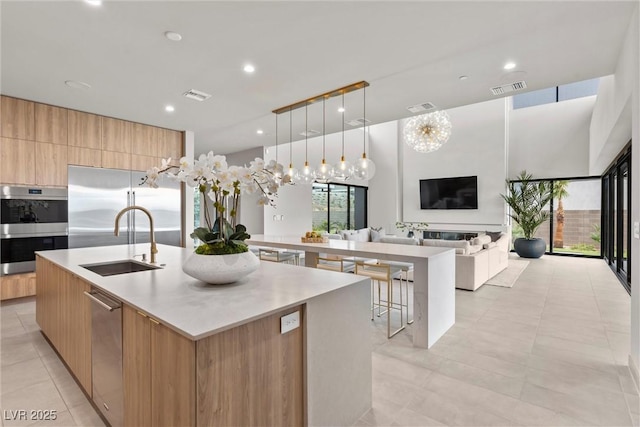 kitchen featuring a spacious island, light countertops, appliances with stainless steel finishes, a sink, and modern cabinets