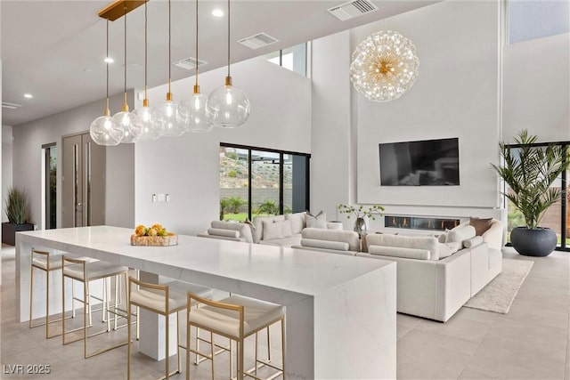 kitchen featuring a breakfast bar, open floor plan, visible vents, and decorative light fixtures