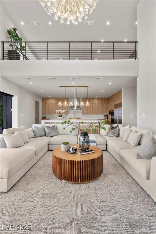 living room featuring visible vents, a notable chandelier, and a high ceiling