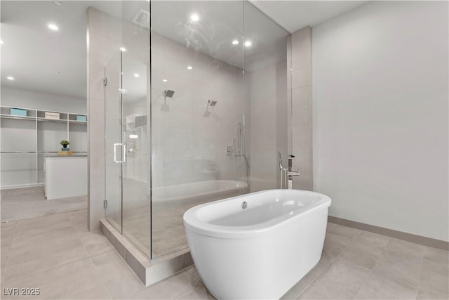 bathroom featuring a freestanding bath, tile patterned flooring, a shower stall, and baseboards