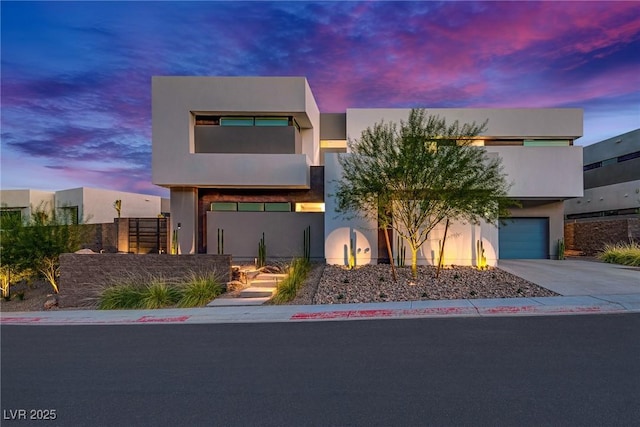 modern home with concrete driveway, an attached garage, and stucco siding