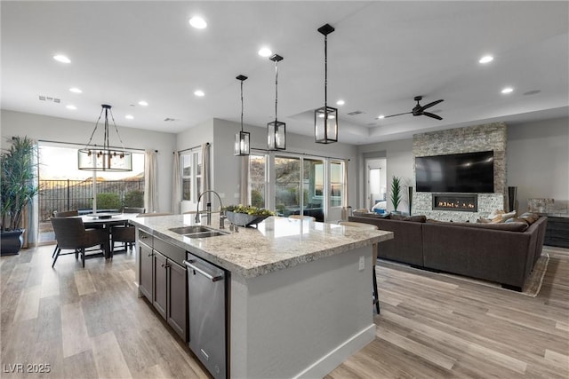 kitchen featuring hanging light fixtures, an island with sink, dishwasher, and sink