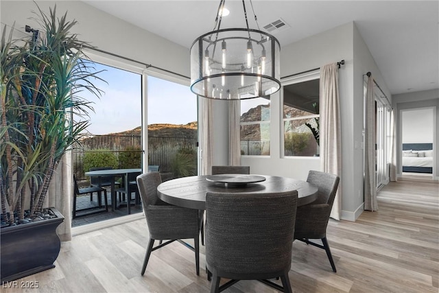 dining space with light hardwood / wood-style flooring and a chandelier