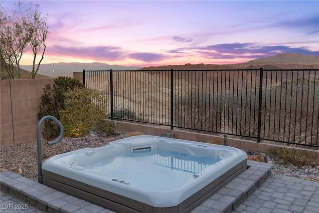 patio terrace at dusk with a mountain view and an outdoor hot tub