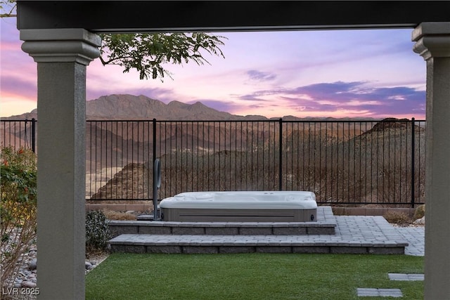 patio terrace at dusk featuring a hot tub and a mountain view