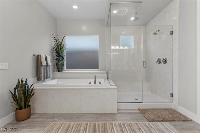 bathroom with independent shower and bath and wood-type flooring