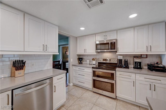 kitchen with white cabinetry, light tile patterned floors, decorative backsplash, and appliances with stainless steel finishes