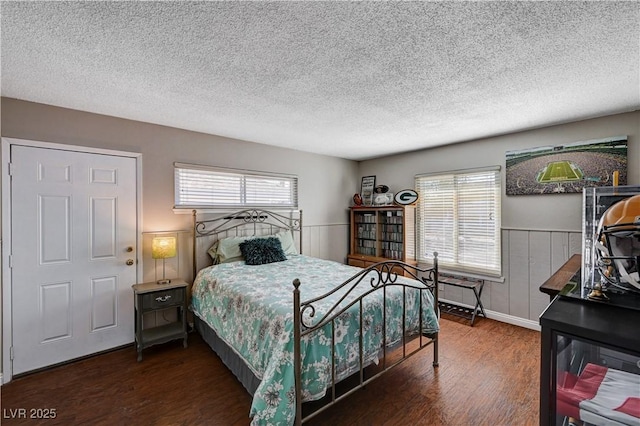 bedroom with multiple windows, a textured ceiling, and dark hardwood / wood-style flooring