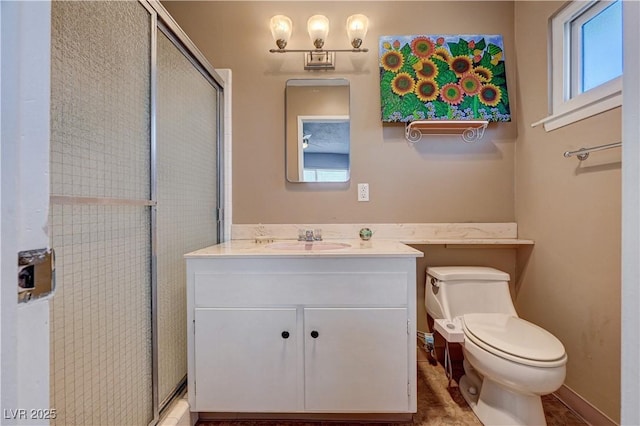 bathroom featuring a shower with door, vanity, and toilet