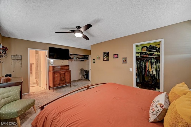 carpeted bedroom featuring ceiling fan, ensuite bathroom, a textured ceiling, a walk in closet, and a closet