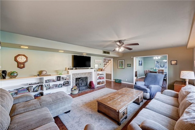 living room featuring wood-type flooring, ceiling fan, and a fireplace