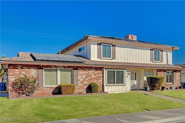 view of front of property with a front yard and solar panels