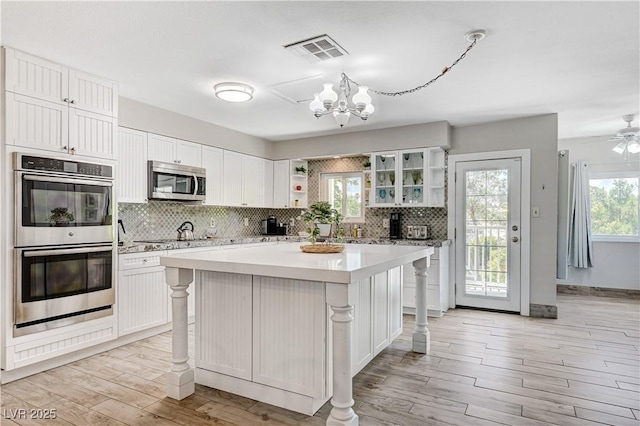 kitchen with stainless steel appliances, a kitchen island, and white cabinets