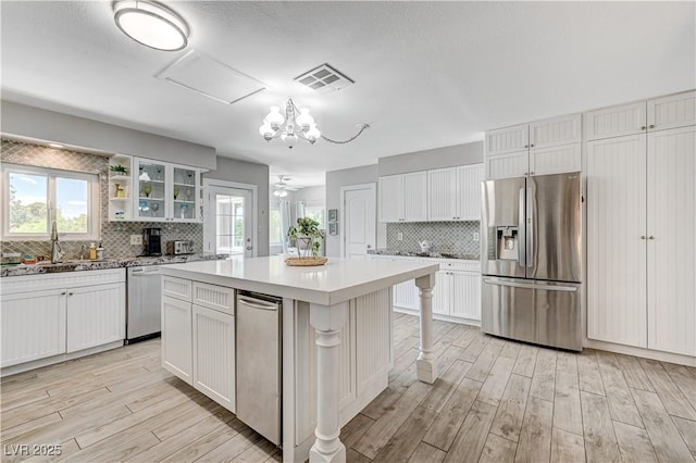 kitchen featuring a kitchen bar, a center island, appliances with stainless steel finishes, light hardwood / wood-style floors, and white cabinets