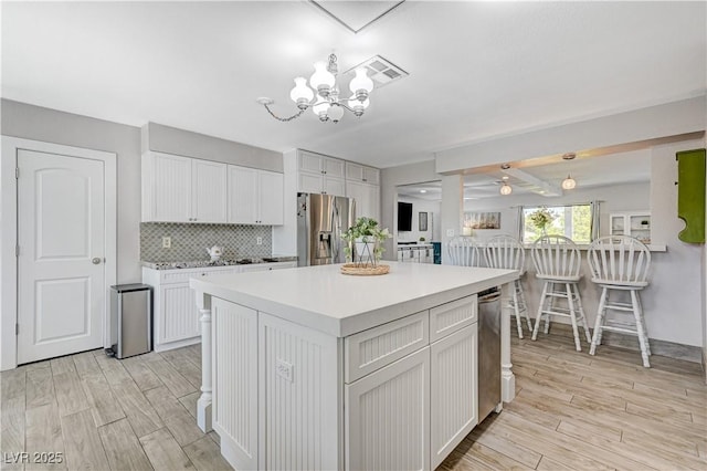 kitchen featuring pendant lighting, stainless steel fridge with ice dispenser, white cabinetry, and a center island