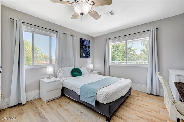 bedroom with ceiling fan, multiple windows, and light hardwood / wood-style flooring