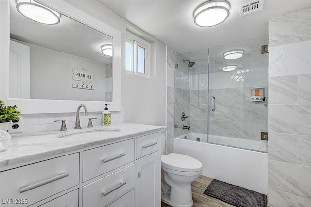 full bathroom featuring vanity, combined bath / shower with glass door, wood-type flooring, and toilet