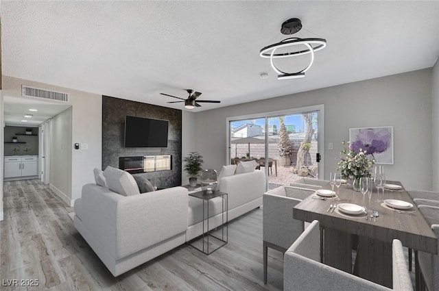 living room featuring ceiling fan, hardwood / wood-style floors, a textured ceiling, and a fireplace