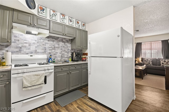 kitchen with tasteful backsplash, sink, dark hardwood / wood-style flooring, white appliances, and a textured ceiling