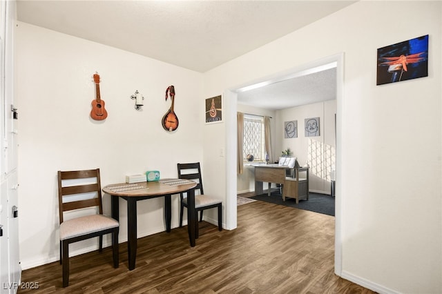 dining area featuring dark wood-type flooring and a textured ceiling