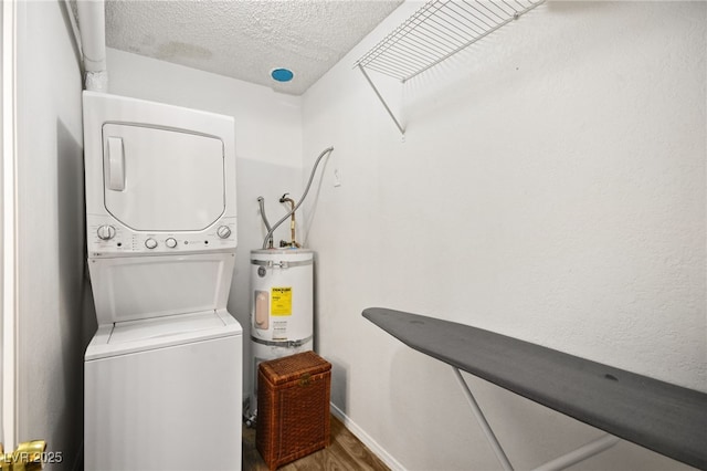 clothes washing area featuring hardwood / wood-style flooring, stacked washing maching and dryer, a textured ceiling, and strapped water heater