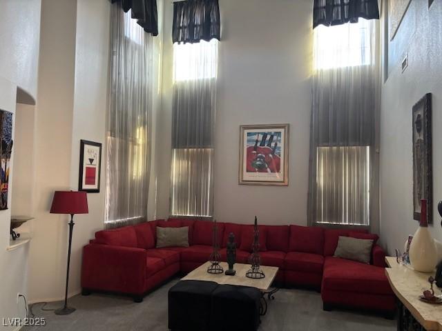 living room with a high ceiling, a wealth of natural light, and light colored carpet