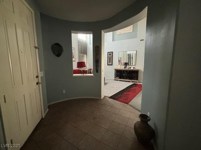 hallway featuring dark tile patterned floors and baseboards