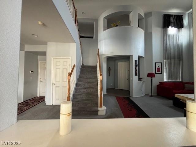 carpeted foyer with stairs and a high ceiling