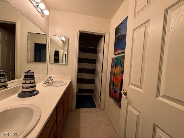 bathroom with tile patterned flooring, a sink, a shower with shower curtain, and double vanity