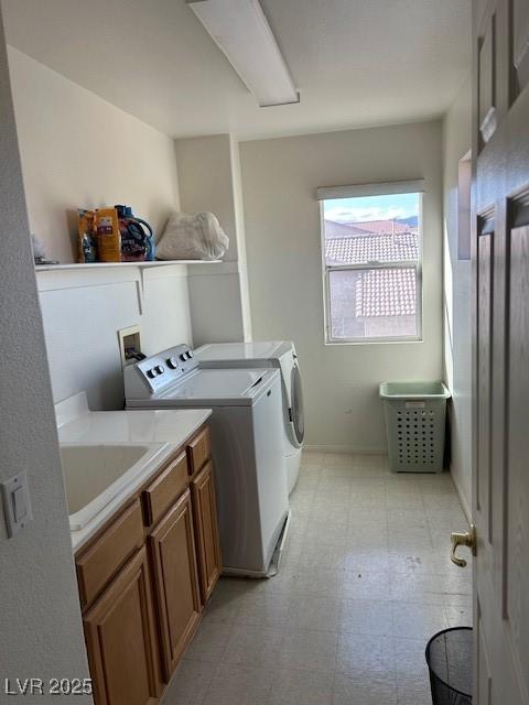 clothes washing area with a sink, light floors, cabinet space, and washer and dryer