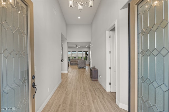 foyer entrance with ceiling fan with notable chandelier and light hardwood / wood-style floors