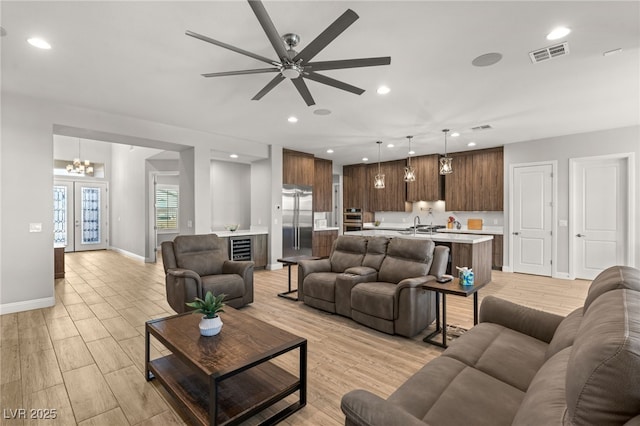 living room with ceiling fan with notable chandelier and light hardwood / wood-style flooring