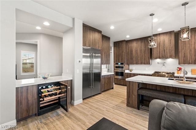 kitchen featuring sink, wine cooler, dark brown cabinetry, stainless steel appliances, and light hardwood / wood-style flooring